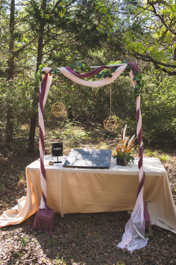 a decorated square arch over a table with the guest book and a matching floral arrangement.